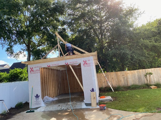 Crew framing roof trusses on a garage addition