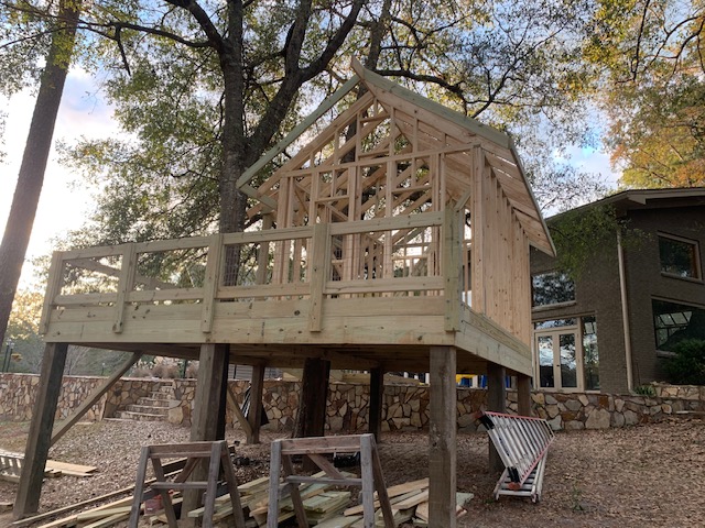 Elevated framed structure on deck posts near a stone wall