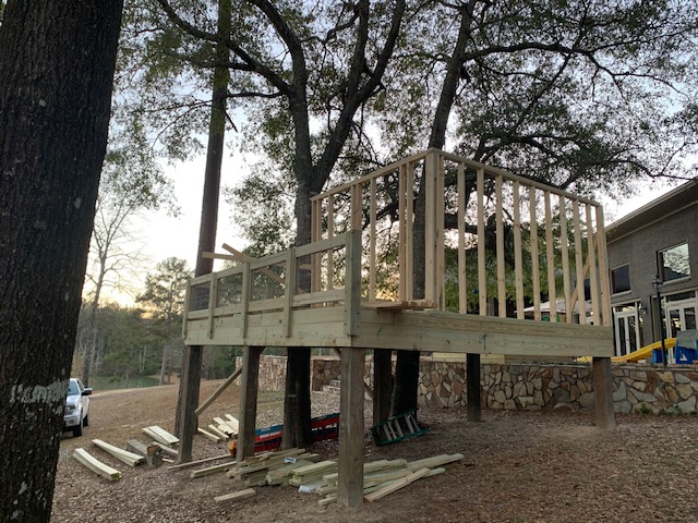 Elevated deck with partial wall framing near a stone retaining wall