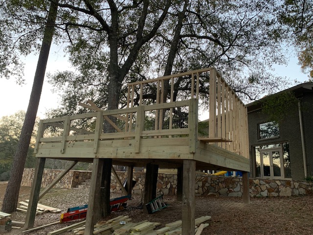 Elevated deck framing at dusk beside the main home