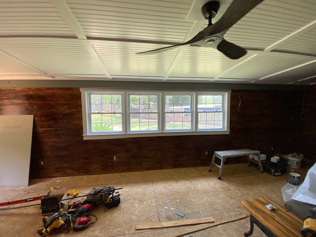 Wood-paneled room addition with ceiling fan and windows