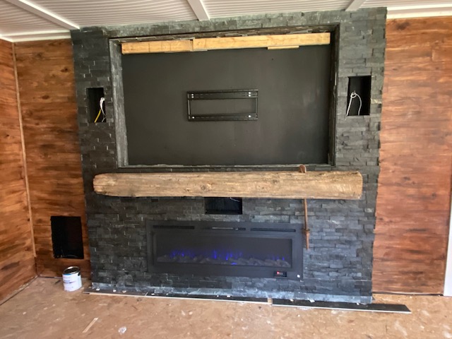 Stacked-stone TV wall with wood mantel and fireplace insert