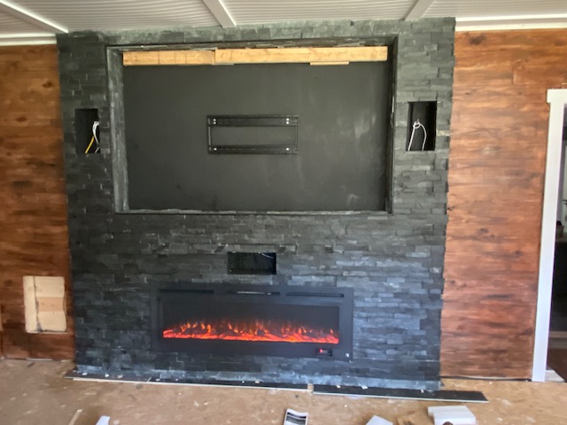 Completed stone fireplace wall with fireplace insert lit