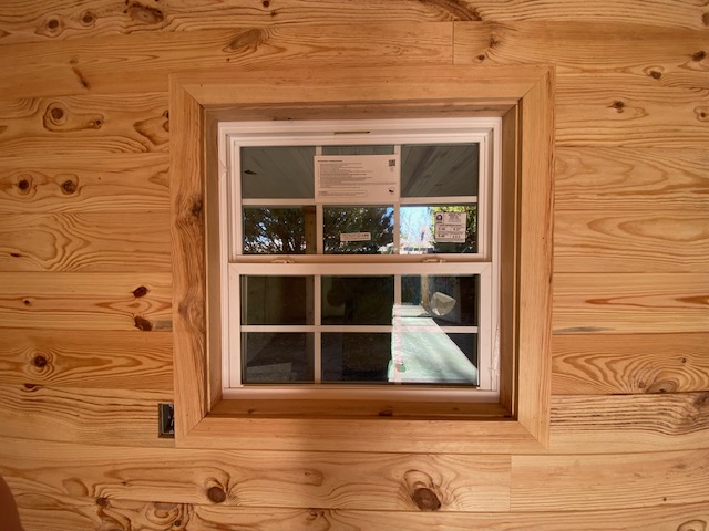 Window trimmed in knotty pine wall paneling