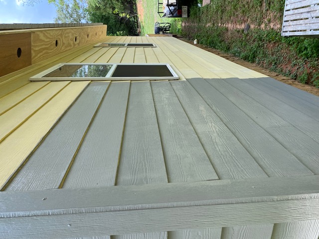 Close-up of freshly painted gray-green lap siding and trim