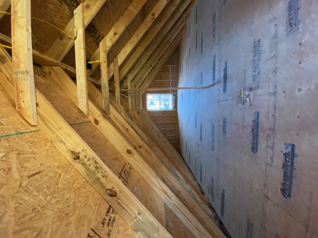 Attic rafters viewed toward a small gable window