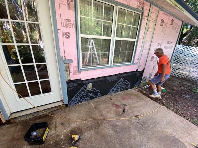 Crew installing siding over house wrap near a window